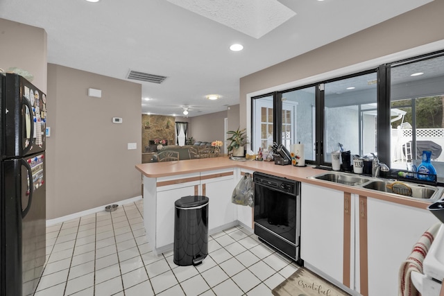 kitchen with kitchen peninsula, sink, black appliances, light tile patterned floors, and white cabinets