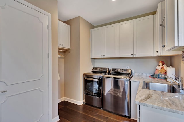 clothes washing area with cabinets, sink, dark wood-type flooring, and washer and clothes dryer