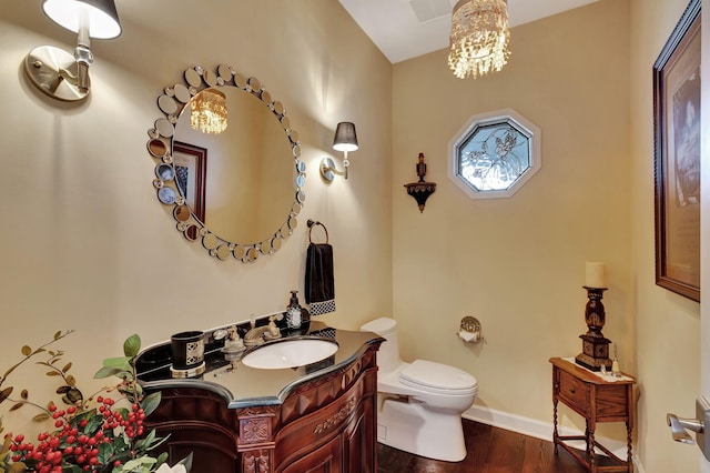 bathroom featuring an inviting chandelier, wood-type flooring, toilet, and vanity