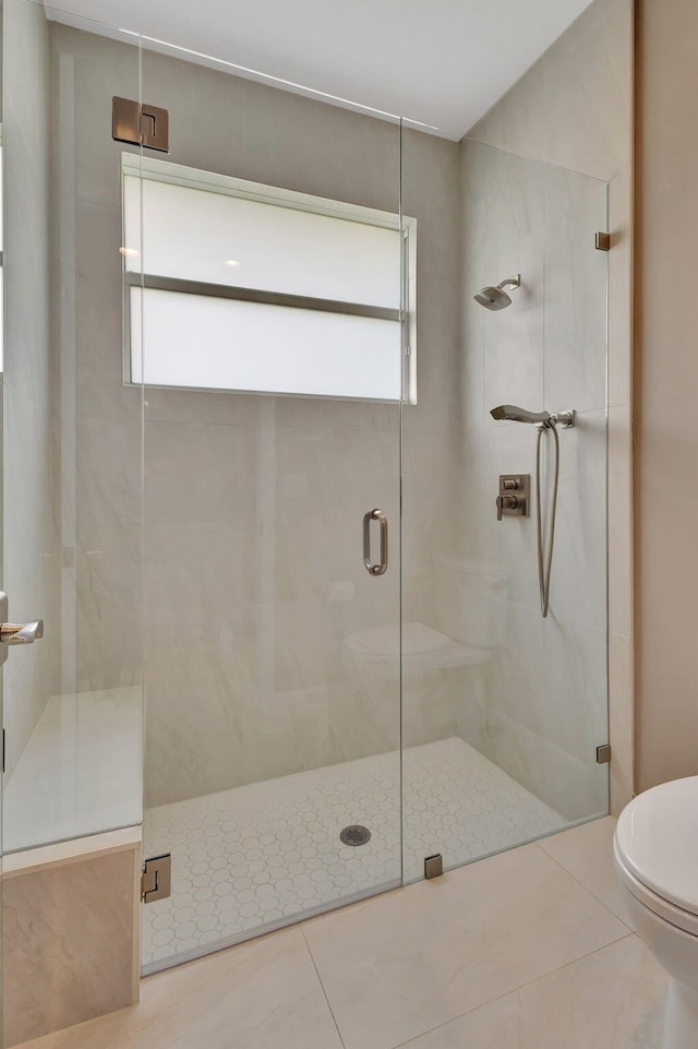 bathroom with tile patterned flooring, toilet, plenty of natural light, and a shower with shower door