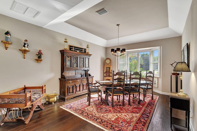 dining area featuring an inviting chandelier, dark hardwood / wood-style flooring, and a raised ceiling