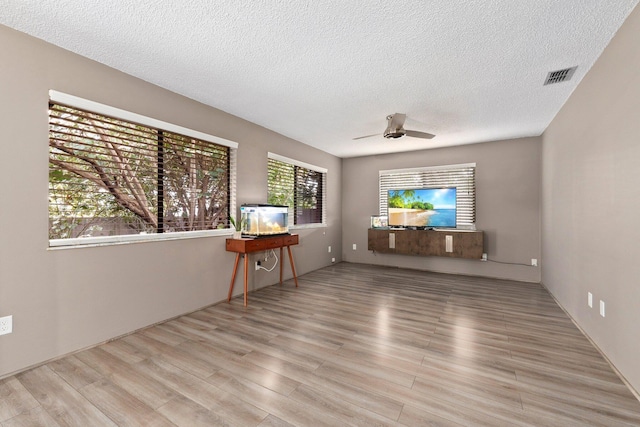 unfurnished living room with ceiling fan, light hardwood / wood-style floors, and a textured ceiling