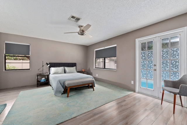 bedroom with access to exterior, ceiling fan, light hardwood / wood-style floors, and a textured ceiling