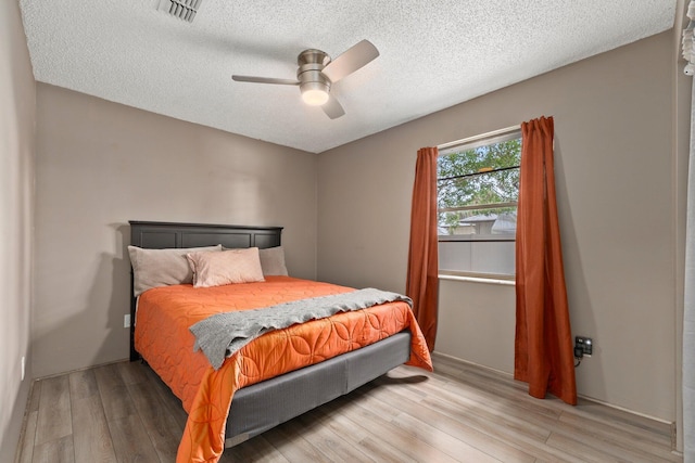 bedroom featuring ceiling fan, light wood-type flooring, and a textured ceiling