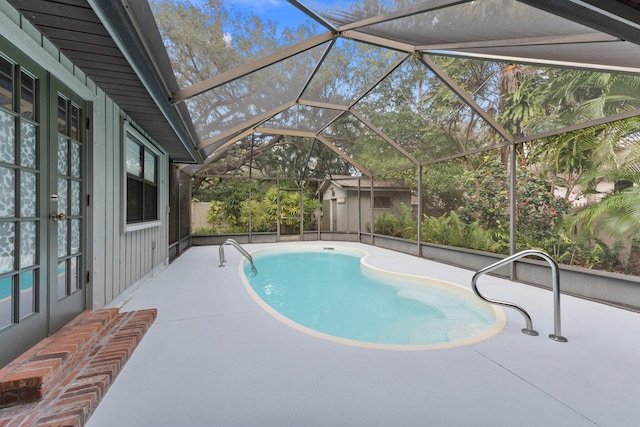 view of pool with a patio, glass enclosure, and a storage shed