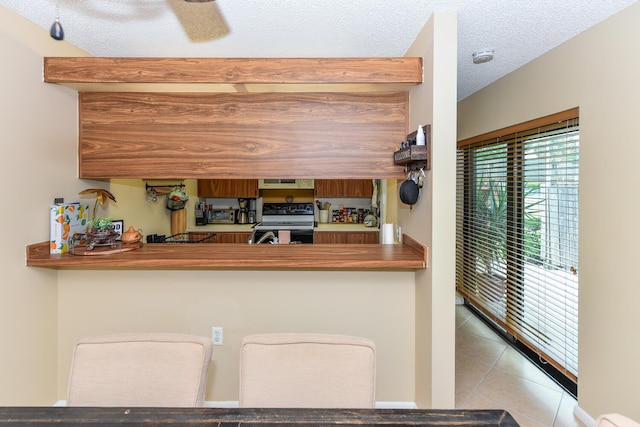 kitchen featuring light tile patterned floors, black electric range oven, and a textured ceiling