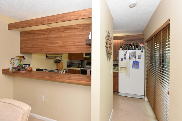 kitchen with light tile patterned floors, white appliances, a textured ceiling, and sink