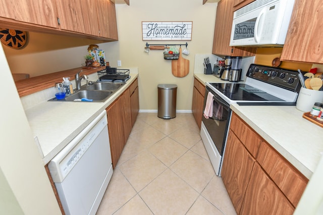 kitchen featuring sink, light tile patterned flooring, and white appliances