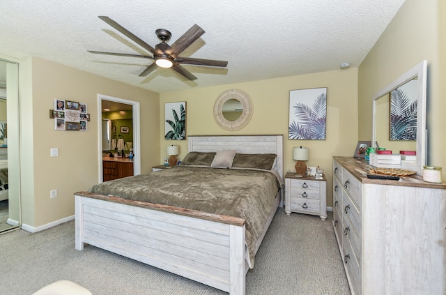 carpeted bedroom featuring ceiling fan, a textured ceiling, and ensuite bath