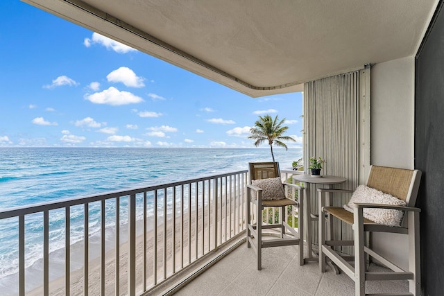 balcony with a water view and a view of the beach