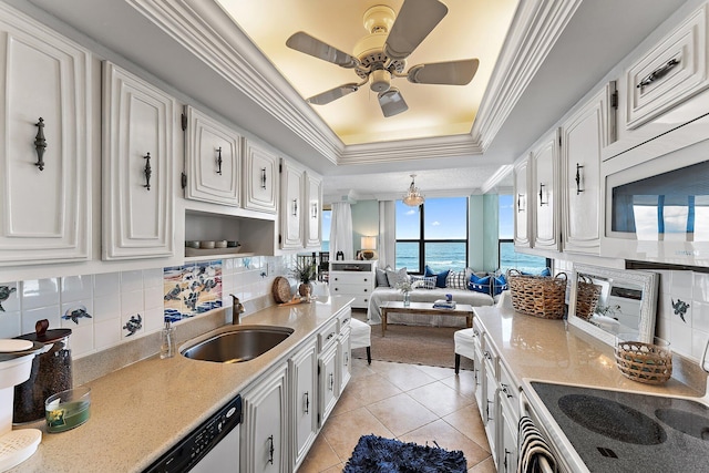 kitchen with stove, white cabinets, a raised ceiling, a water view, and sink