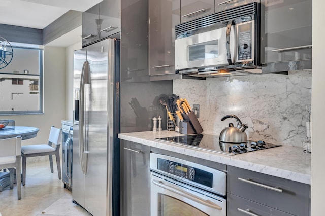 kitchen featuring backsplash, gray cabinets, light tile patterned floors, and appliances with stainless steel finishes