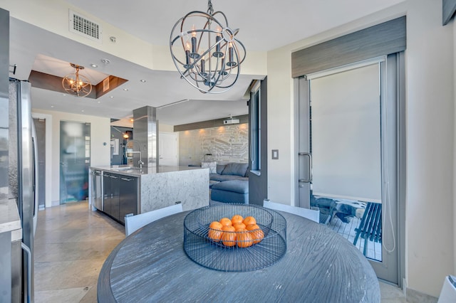 dining room with a tray ceiling, sink, and a chandelier