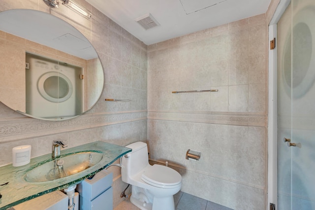 bathroom featuring tile patterned floors, toilet, sink, and tile walls