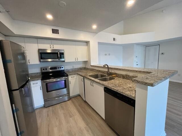 kitchen with sink, stainless steel appliances, white cabinetry, and kitchen peninsula