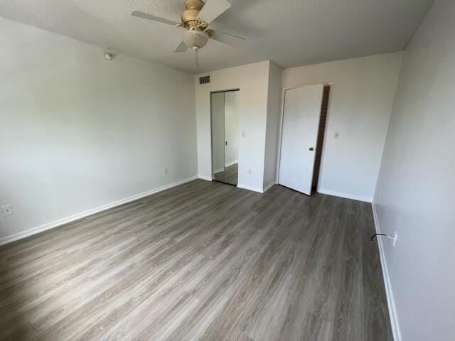 unfurnished room with ceiling fan, a textured ceiling, and dark hardwood / wood-style flooring