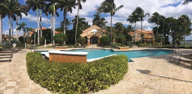 view of swimming pool featuring a hot tub and a patio