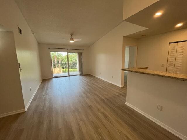 unfurnished living room with ceiling fan and dark wood-type flooring