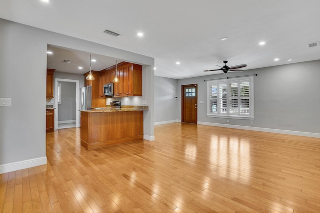 kitchen featuring ceiling fan, stainless steel appliances, kitchen peninsula, light hardwood / wood-style floors, and decorative light fixtures