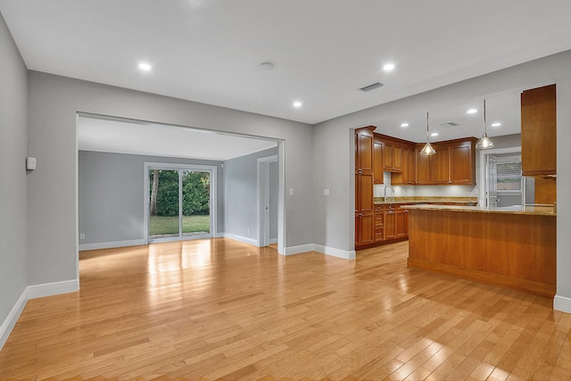 kitchen with sink, light wood-type flooring, kitchen peninsula, and hanging light fixtures