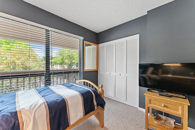 carpeted bedroom with multiple windows, a textured ceiling, and a closet