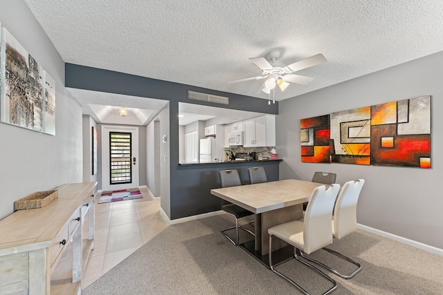 dining space with ceiling fan, light tile patterned flooring, and a textured ceiling