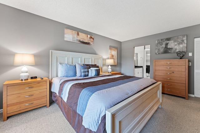 carpeted bedroom featuring ensuite bath and a textured ceiling