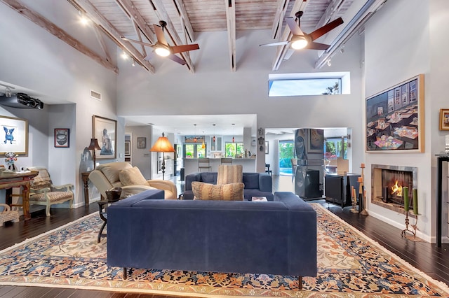 living room featuring a high ceiling, rail lighting, beam ceiling, and dark wood-type flooring