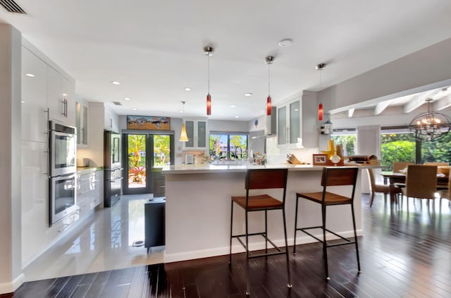 kitchen with decorative light fixtures, decorative backsplash, a wealth of natural light, white cabinetry, and appliances with stainless steel finishes