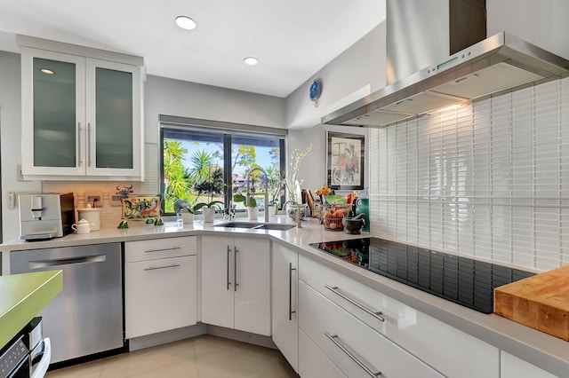 kitchen featuring white cabinetry, wall chimney range hood, black electric stovetop, sink, and stainless steel dishwasher