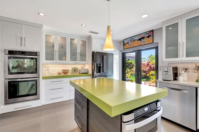 kitchen with backsplash, a kitchen island, pendant lighting, white cabinetry, and stainless steel appliances