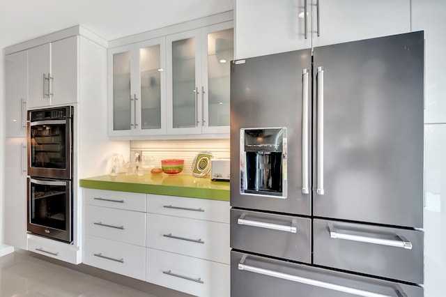 kitchen featuring backsplash, white cabinetry, and stainless steel appliances