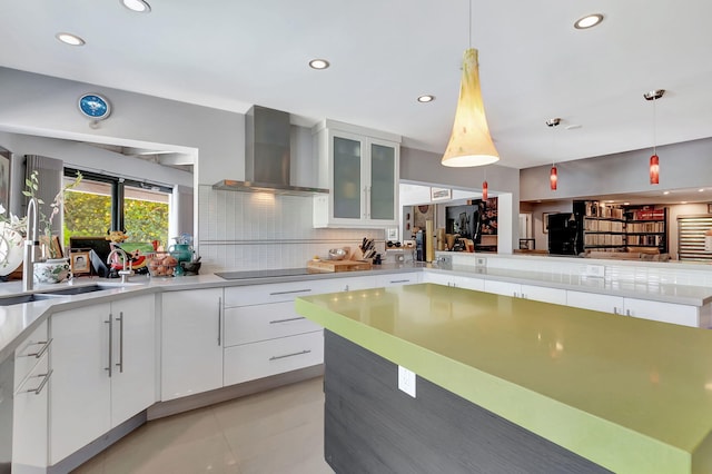 kitchen featuring wall chimney exhaust hood, white cabinets, and decorative light fixtures