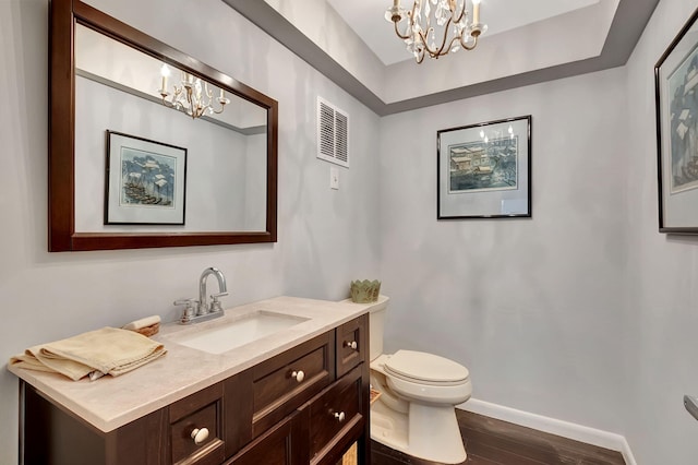 bathroom featuring toilet, vanity, wood-type flooring, and a notable chandelier