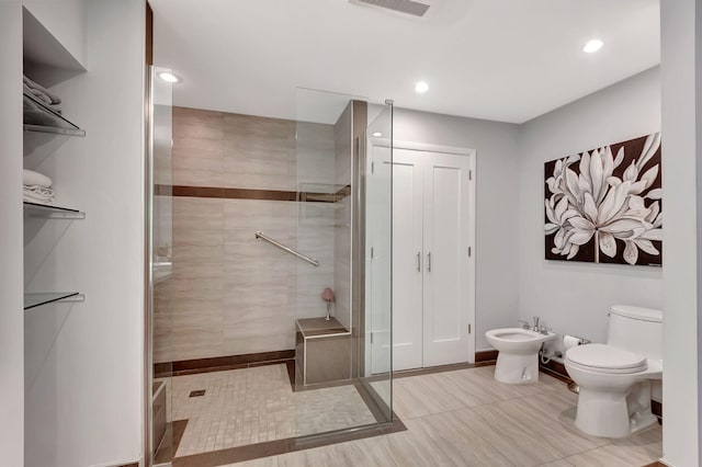 bathroom with toilet, tiled shower, and a bidet