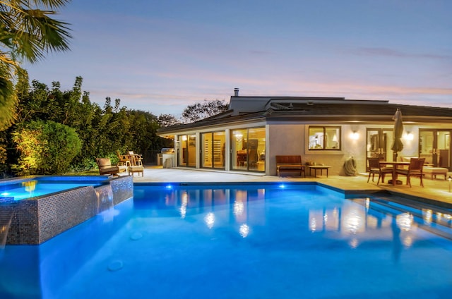 pool at dusk featuring a patio