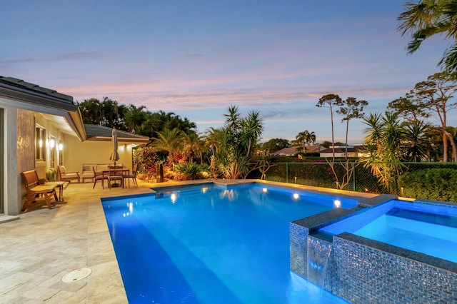 pool at dusk featuring a patio area, outdoor lounge area, and an in ground hot tub