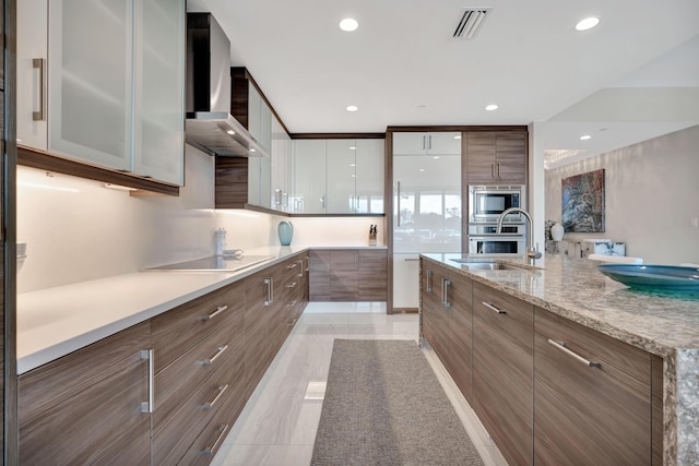 kitchen with light stone countertops, wall chimney exhaust hood, white cabinetry, appliances with stainless steel finishes, and sink