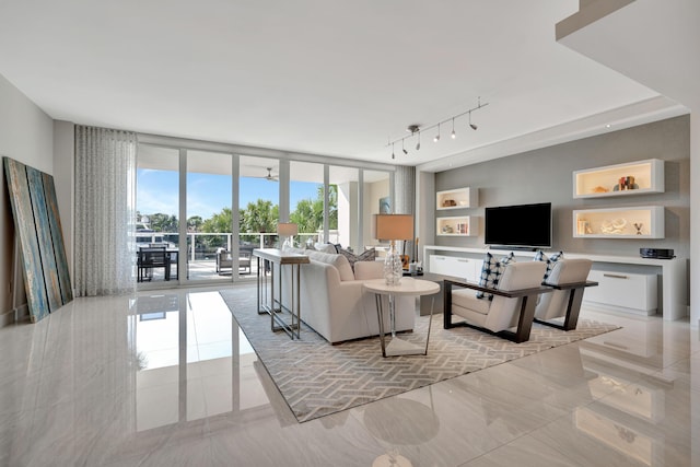 living room featuring ceiling fan and expansive windows