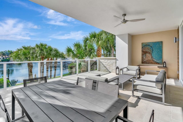 wooden deck with an outdoor hangout area, ceiling fan, and a water view