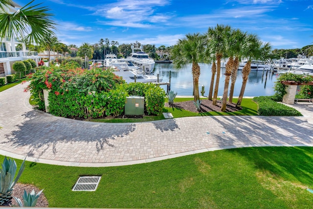 view of home's community with a dock, a lawn, and a water view