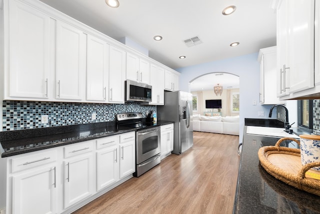 kitchen featuring stainless steel appliances, white cabinetry, dark stone countertops, and light hardwood / wood-style floors