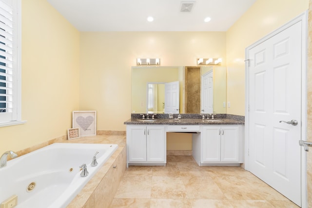 bathroom featuring tiled tub and vanity