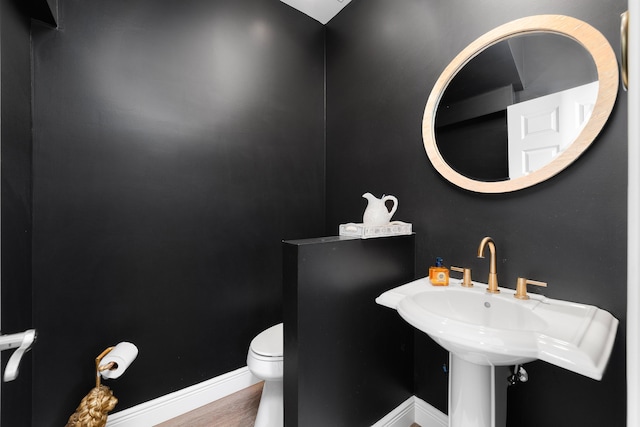 bathroom with toilet, wood-type flooring, and sink