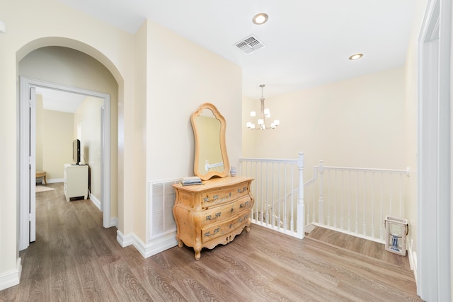 hall featuring an inviting chandelier and hardwood / wood-style flooring