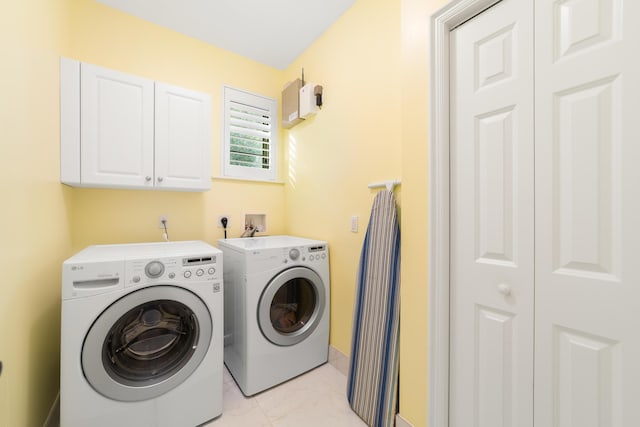 washroom featuring cabinets, washing machine and dryer, and light tile patterned flooring