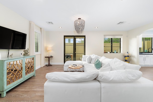 living room featuring sink, light wood-type flooring, and french doors