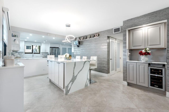 kitchen featuring a center island, beverage cooler, an inviting chandelier, stainless steel fridge with ice dispenser, and decorative light fixtures