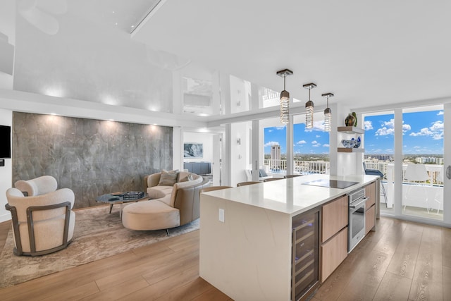 kitchen with floor to ceiling windows, hanging light fixtures, beverage cooler, oven, and a kitchen island