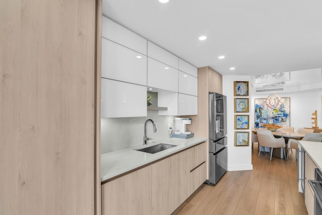 kitchen featuring stainless steel refrigerator with ice dispenser, light wood-type flooring, backsplash, sink, and white cabinets